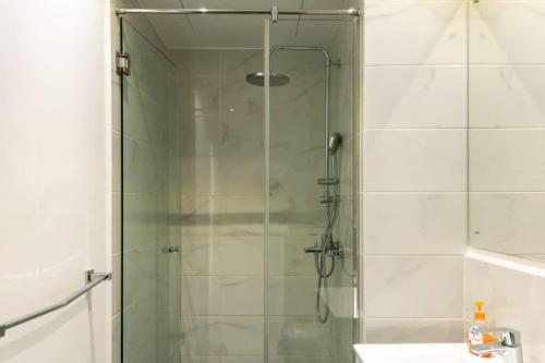 a shower with a glass door in a bathroom at Cosy 2 Bed at Embassy Gardens in Cantonments