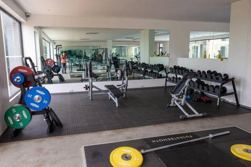 a gym with a lot of equipment and a mirror at Cosy 2 Bed at Embassy Gardens in Cantonments