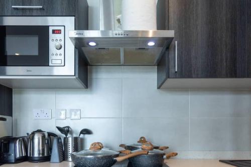 a kitchen with a stove top with pots and pans at Cosy 2 Bed at Embassy Gardens in Cantonments