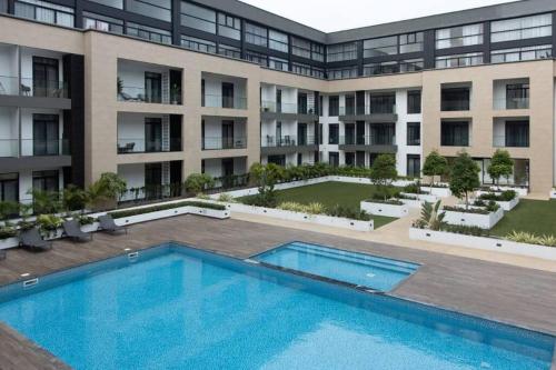 an exterior view of a building with a swimming pool at Cosy 2 Bed at Embassy Gardens in Cantonments