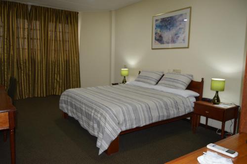 a bedroom with a bed and a lamp at The Golden Truly Hotel & Casino in Paramaribo