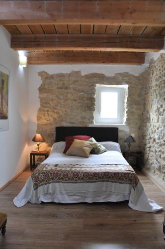 une chambre avec un grand lit dans un mur de pierre dans l'établissement La Grange, à Saint-Sauveur-de-Cruzières