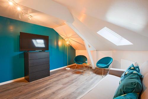 a room with a couch and a television in a attic at Le Havre - Quartier des Docks au Calme - 4 Appartements Entièrement Rénovés - NOUVEAU in Le Havre