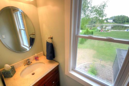 a bathroom with a sink and a mirror and a window at Riverfront Retreat! Water front and dog friendly! in Two Rivers