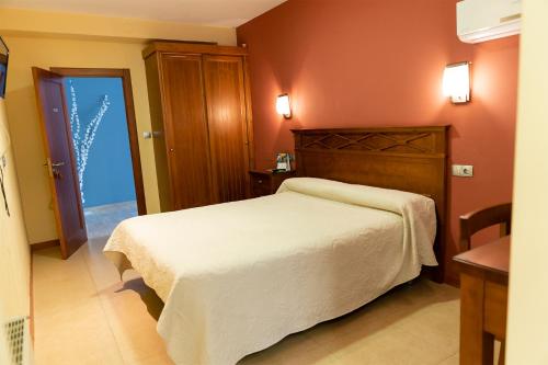 1 dormitorio con cama blanca y cabecero de madera en Pensión Restaurante Casablanca, en Torreperogil