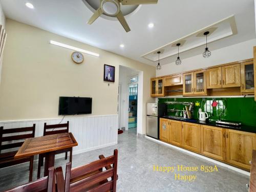 een woonkamer met een tafel en een televisie en een keuken bij Căn Happy in Vung Tau