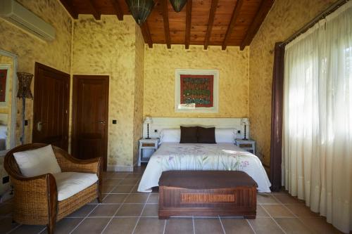 a bedroom with a bed and a chair at Hotel El Mirlo Blanco in Candeleda