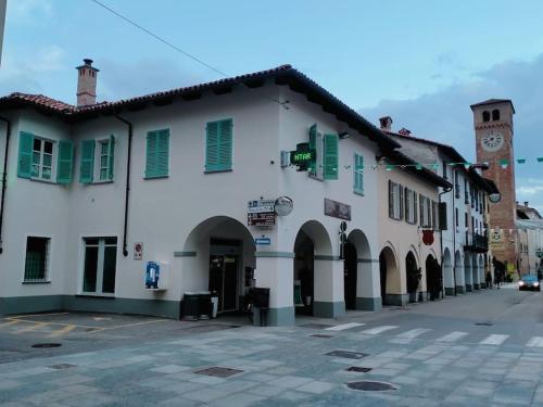 a large white building with green windows and a clock tower at B&B San Gregorio in Cherasco
