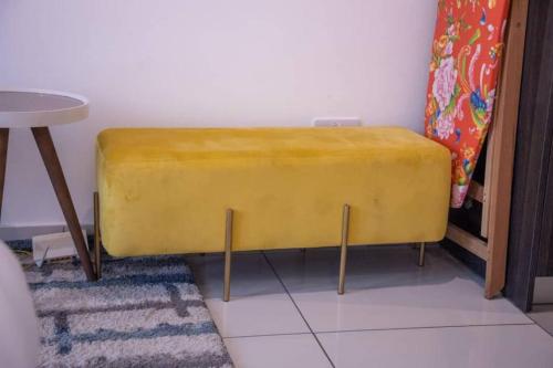 a yellow bench in a room with a table at Deluxe Studio at Embassy Gardens Cantonments in Cantonments