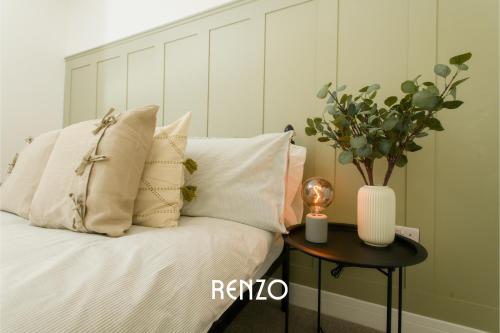a bed with pillows and a table with a vase on it at Incredible 2 Bedroom Home in Lincoln by Renzo, Close to Lincoln Cathedral! in Lincolnshire