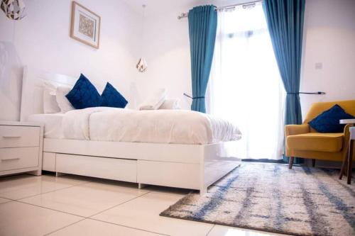 a white bed with blue pillows in a bedroom at Deluxe Studio at Embassy Gardens Cantonments in Cantonments