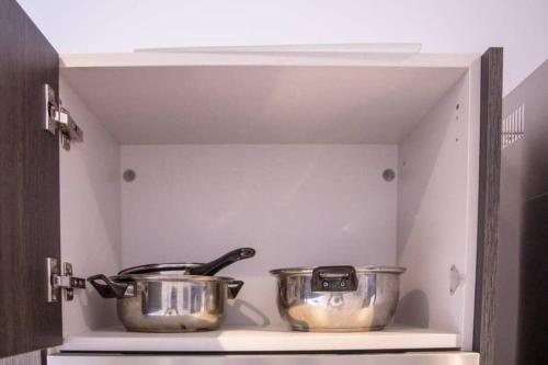 two pots and pans sitting on a shelf in a kitchen at Deluxe Studio at Embassy Gardens Cantonments in Cantonments