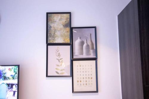 four framed pictures on a white wall with a shelf at Deluxe Studio at Embassy Gardens Cantonments in Cantonments