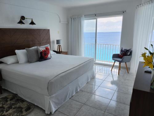 Coral Princess Hotel & Dive Resort في كوزوميل: غرفة نوم مع سرير وإطلالة على المحيط