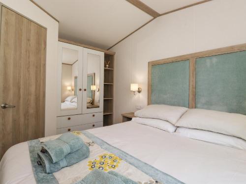 ein Schlafzimmer mit einem großen weißen Bett und einem Spiegel in der Unterkunft 29 Lakes View in Carnforth