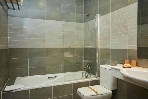 y baño con bañera, aseo y lavamanos. en Hotel El Mirlo Blanco en Candeleda