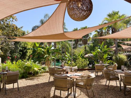 um pátio exterior com mesas, cadeiras e guarda-sóis em Cannes Villa St Barth em Cannes