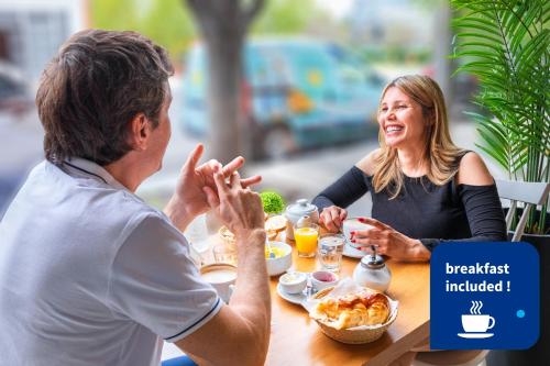 Un uomo e una donna seduti a tavola mangiando cibo di Trendy Apartments in Palermo a Buenos Aires