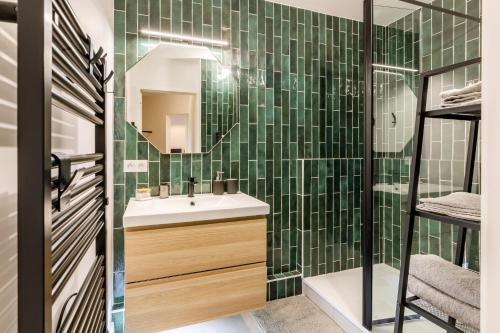 un bagno piastrellato verde con lavandino e specchio di Le Dobrée - Centre - Charme & Confort - 4p - 55m2 a Nantes