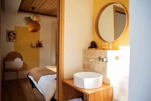 ein Bad mit einem Waschbecken und einem Spiegel in der Unterkunft Dans les Arbres in Lanta