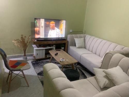uma sala de estar com um sofá branco e uma televisão em Nyumbani kuzuri em Nakuru