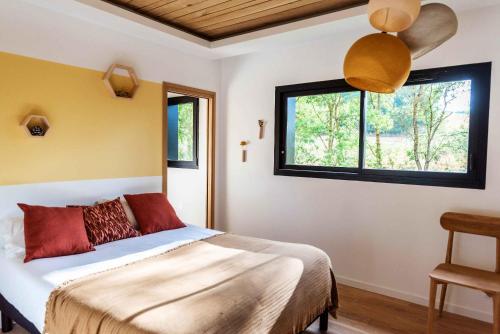 ein Schlafzimmer mit einem Bett und zwei Fenstern in der Unterkunft Dans les Arbres in Lanta