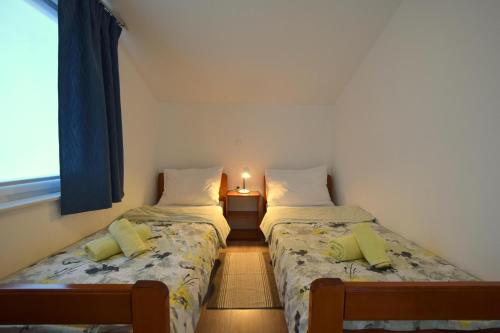 two beds in a small room with a window at Apartments Cindric in Malinska