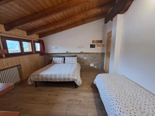 a bedroom with two beds in a room with wooden ceilings at B&B La vecchia posta in Antronapiana