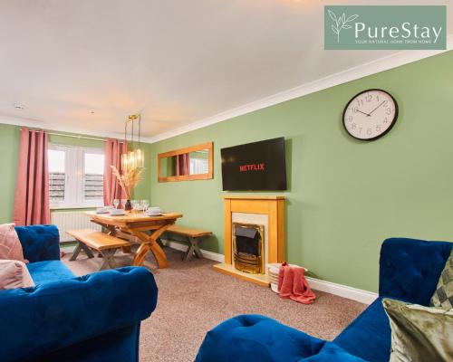 a living room with a table and a clock on the wall at Stunning 6-Bedroom House in Nantwich with Parking & Free Wi-Fi by PureStay Short Lets in Nantwich