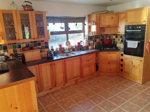 uma cozinha com armários de madeira e piso em azulejo em Ocean Winds em Wexford