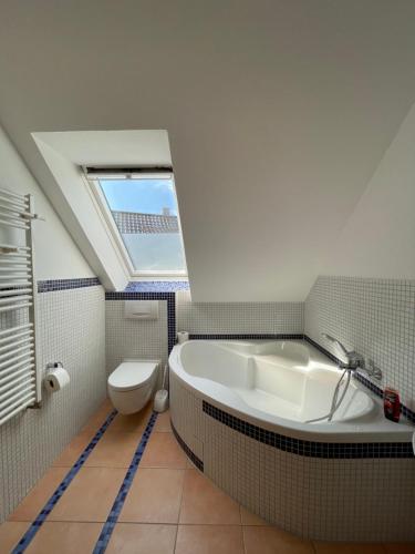 uma casa de banho com uma banheira, um WC e uma clarabóia em Messe Apartment - 10 Gäste em Hanôver