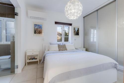 a white bedroom with a large bed and a chandelier at Casa Alma - V027 in Lagos