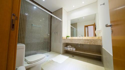 a bathroom with a toilet and a sink and a mirror at Otho Hotel Convention & SPA in Itu