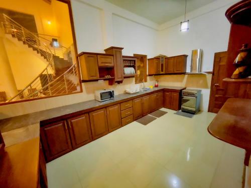 a large kitchen with wooden cabinets and a staircase at Fortress Gate Bungalow in Polonnaruwa