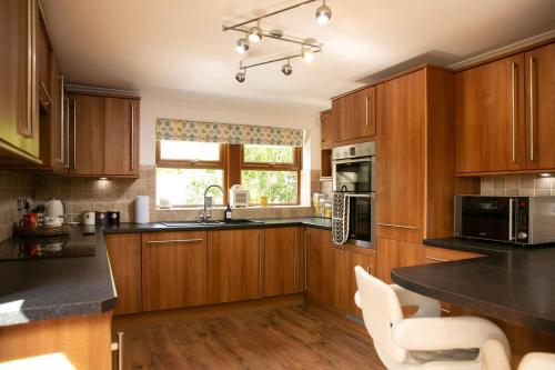 una cocina con armarios de madera y encimeras negras en Remarkable 4-Bed House Near Leeds Airport en Yeadon