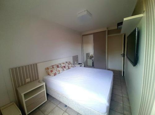 Dormitorio pequeño con cama blanca y TV en Cond. Costa Blanca, Canasvieiras, en Florianópolis