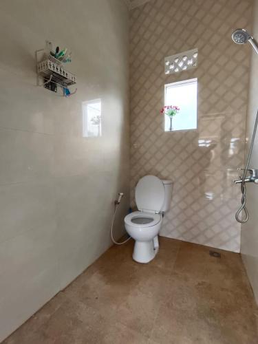 a bathroom with a white toilet and a window at Villa Cisarua Ananda in Brujul