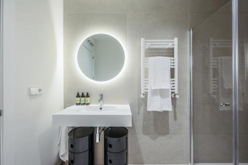 a bathroom with a sink and a shower with a mirror at AmazINN Places Palacio Real in Madrid