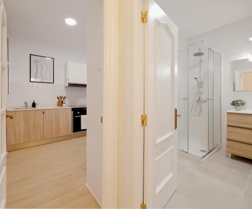 uma casa de banho branca com um chuveiro e um lavatório. em Emilio Tuya 60 em Gijón