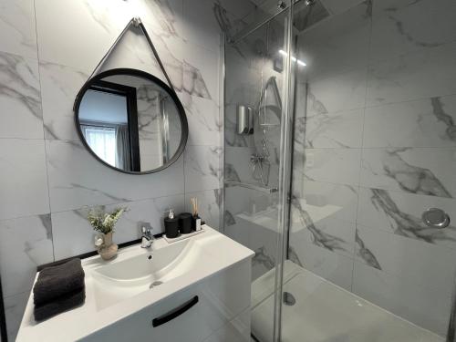 La salle de bains blanche est pourvue d'un lavabo et d'un miroir. dans l'établissement Ferme du Château Fontaine, à Fontaine-lʼÉvêque