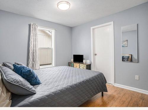 ein Schlafzimmer mit einem Bett mit blauen Kissen und einem Fenster in der Unterkunft Adorable House on Gun Lake in Wayland