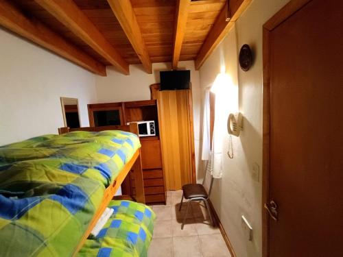 a bedroom with a bed and a room with a microwave at Dormi del Pellin in San Martín de los Andes