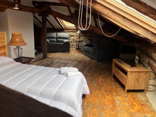 Casa Rural Basiver - Suite Basiver في Armaño: غرفة نوم بسرير وتلفزيون وأريكة