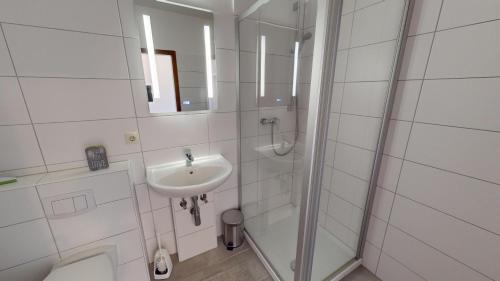 biała łazienka z umywalką i prysznicem w obiekcie Mehrfamilienhaus "Ostseeblick" App 16 w mieście Pelzerhaken