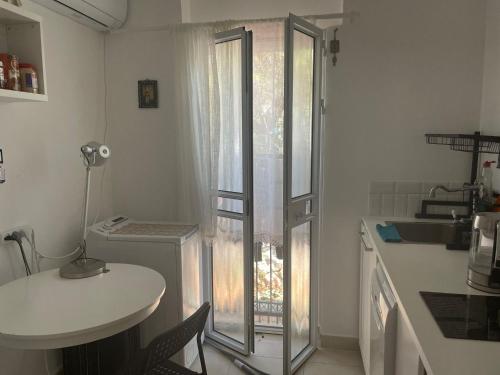 een kleine keuken met een glazen deur naar een raam bij my holiday apartment in Zikhron Ya‘aqov