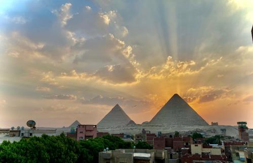 einen Blick auf die Pyramiden von Giza bei Sonnenuntergang in der Unterkunft Pyramids hills view apartment in Kairo