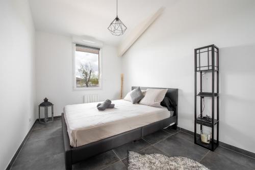 sypialnia z łóżkiem z białymi ścianami i oknem w obiekcie Les terrasses - T3 Spacieux avec parking gratuit w Tuluzie