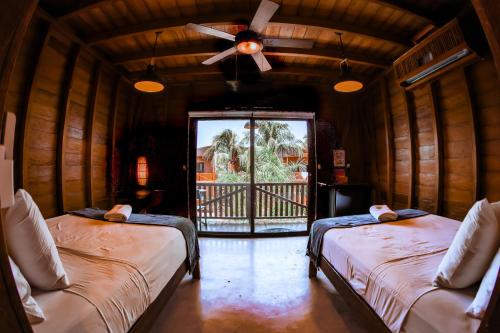 Cette chambre comprend deux lits et un ventilateur de plafond. dans l'établissement Cabañas Coconut by MIJ, à Holbox