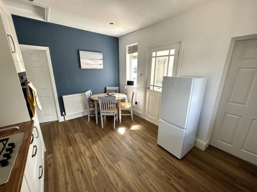 a kitchen with a table and a white refrigerator at Seaside Snug - Gorgeous 2 Bed Seaside Bungalow in Hornsea