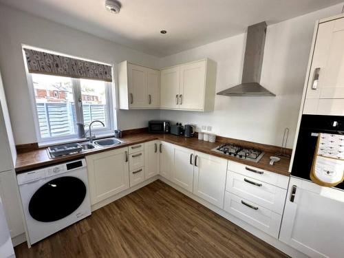 a kitchen with white cabinets and a sink and a stove at Seaside Snug - Gorgeous 2 Bed Seaside Bungalow in Hornsea